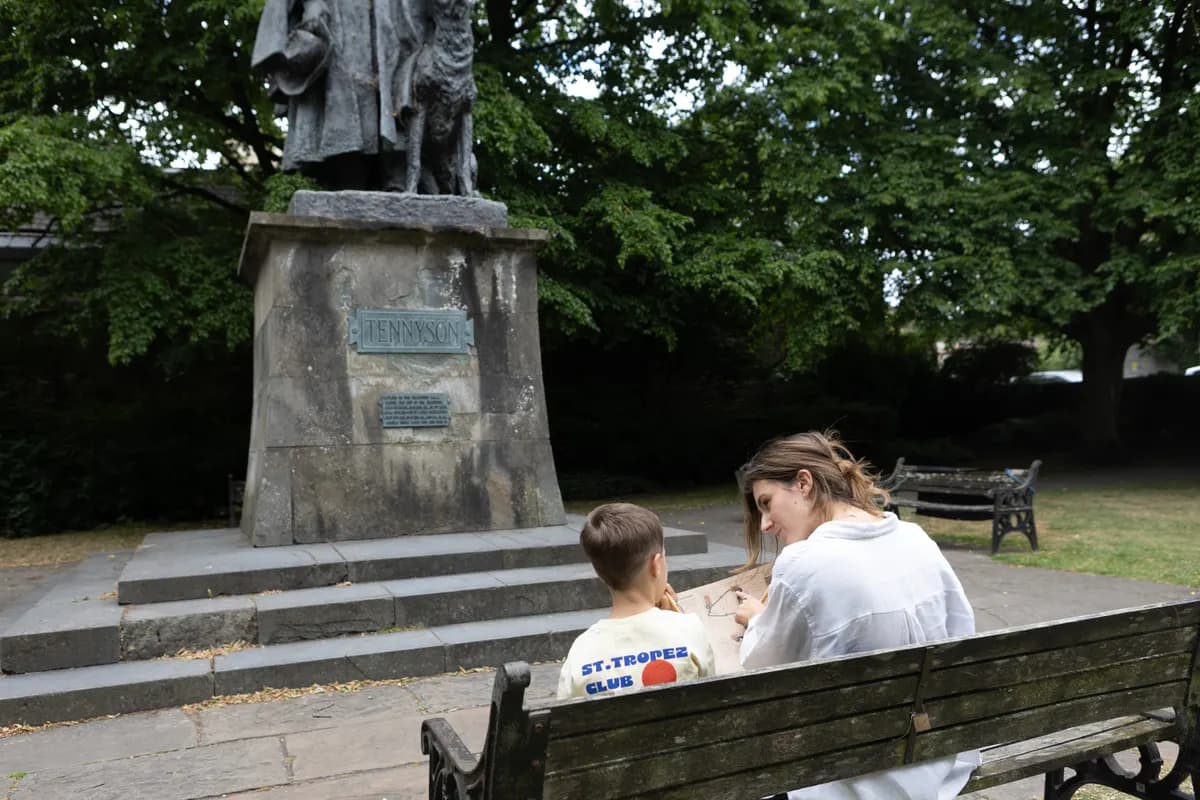 A parent and child solving a quest clue by the Tennyson statue in Lincoln